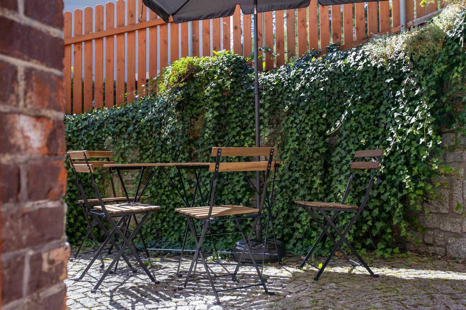 Krzesła bistro na tle ściany porośniętej bluszczem