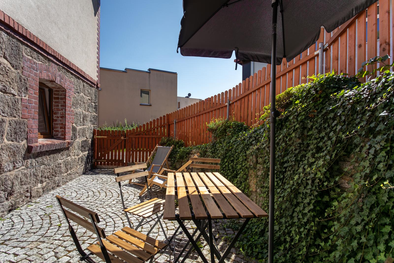 Patio przy kamiennej ścianie budynku z drewnianym stolikiem i leżakami